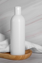 Shampoo bottle and towel on white marble table