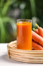 Photo of Tasty juice and carrots on white table outdoors, closeup