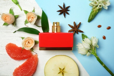 Photo of Beautiful composition with bottle of perfume, flowers and fruits on color background, flat lay