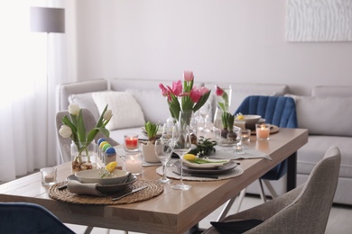 Photo of Beautiful Easter table setting with beautiful flowers in living room