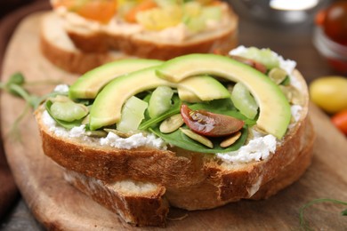 Tasty vegan sandwich with avocado, tomato and spinach on wooden board, closeup