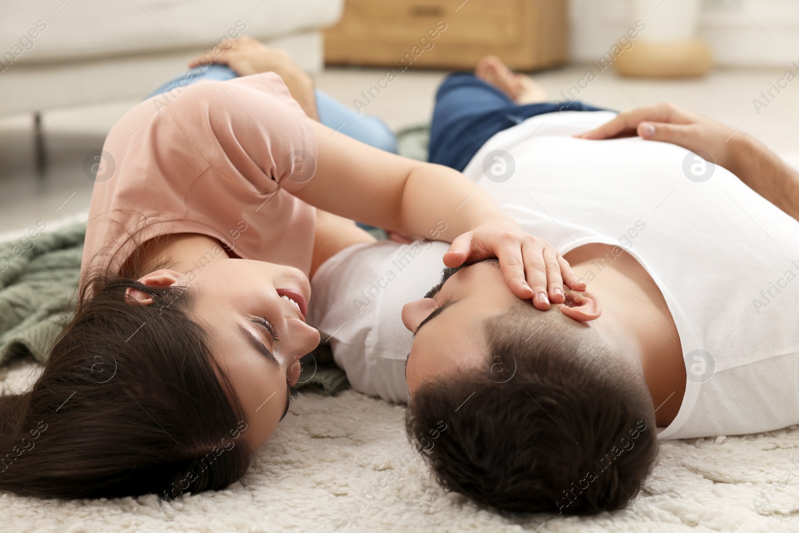 Photo of Affectionate young couple spending time together on soft carpet at home