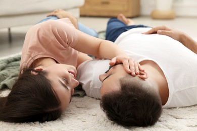 Affectionate young couple spending time together on soft carpet at home