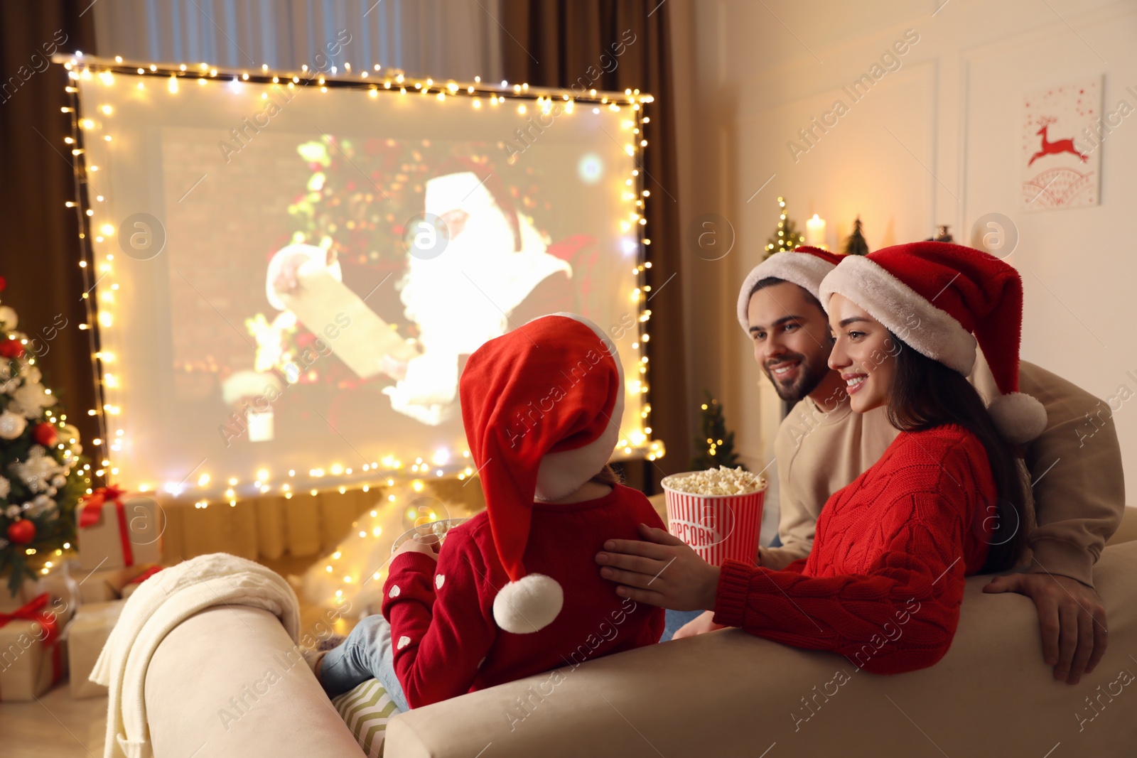 Photo of Family watching movie on projection screen in room decorated for Christmas. Home TV equipment