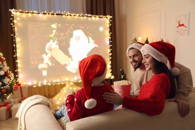 Photo of Family watching movie on projection screen in room decorated for Christmas. Home TV equipment