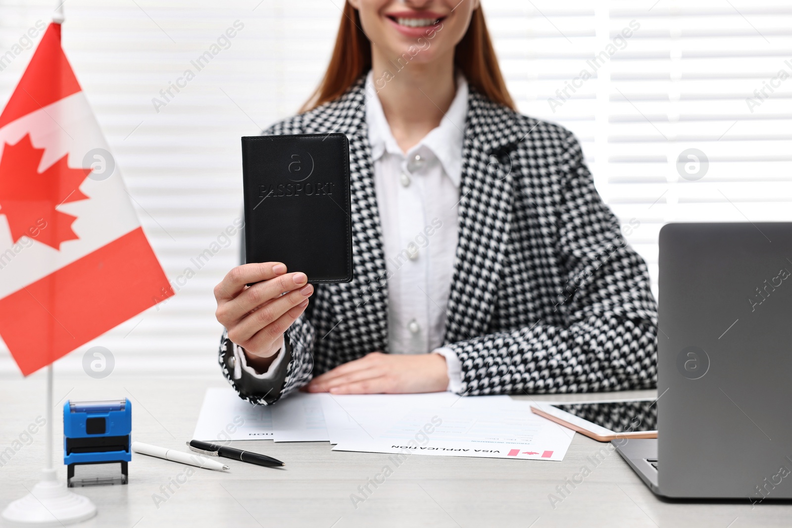 Photo of Immigration to Canada. Smiling embassy worker with passport and documents at table in office, closeup