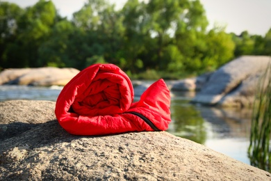 Photo of Rolled sleeping bag near lake on sunny day