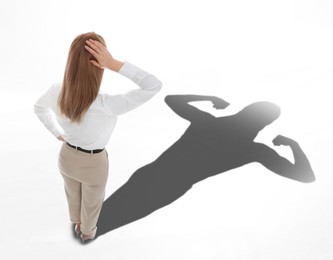 Image of Businesswoman and shadow of strong muscular lady in front of her on white background. Concept of inner strength