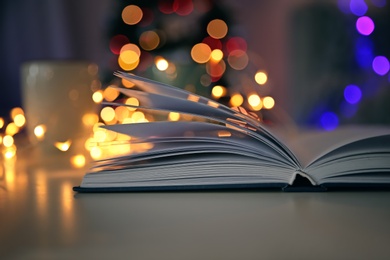 Photo of Open book and blurred Christmas tree on background