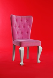 Photo of Stylish pink chair on red background. Element of interior design