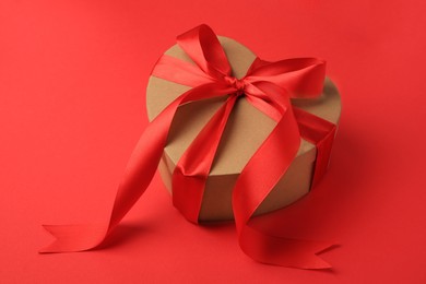 Photo of Beautiful heart shaped gift box with bow on red background