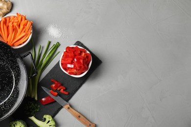 Wok pan and different vegetables on light grey table, flat lay. Space for text