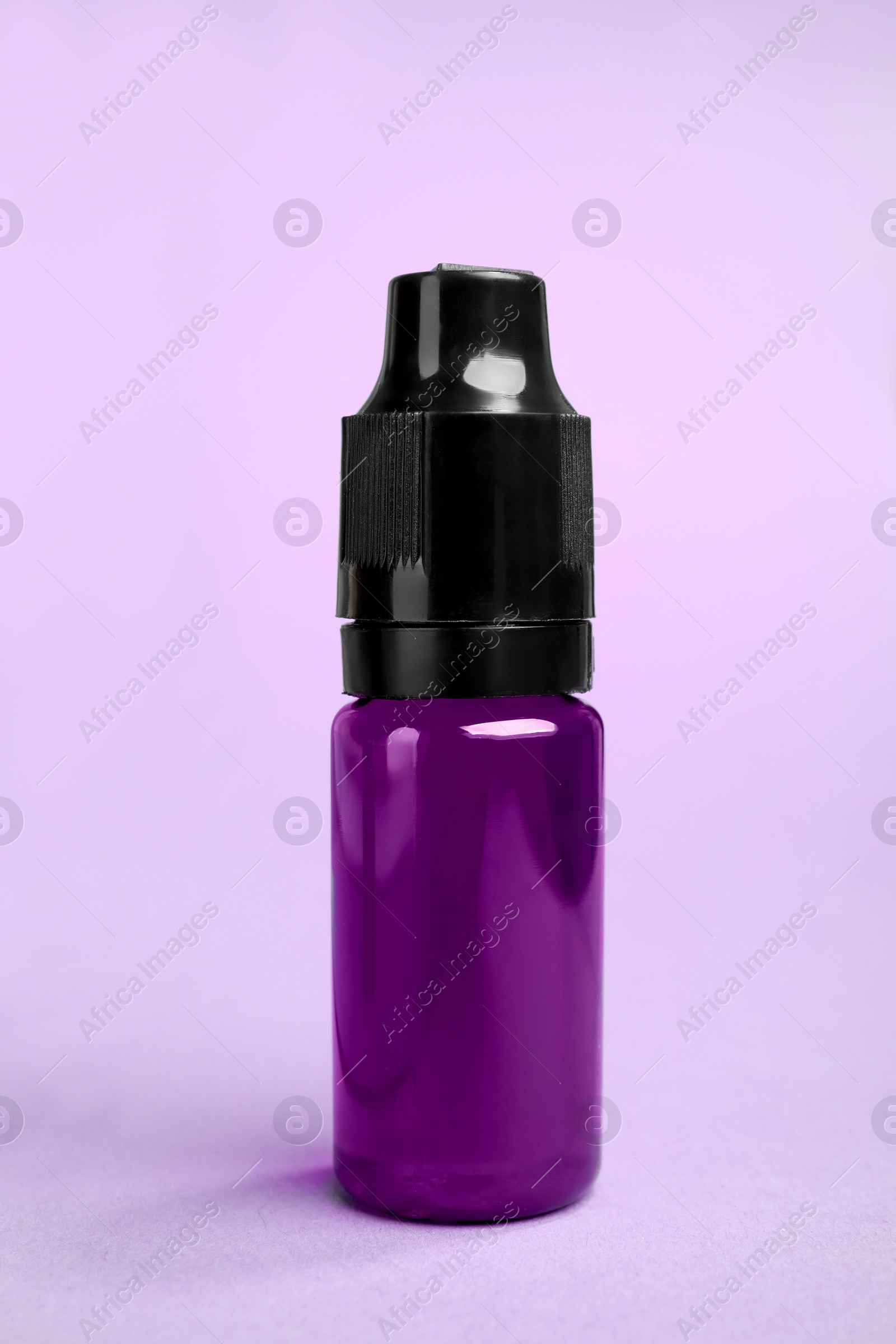Photo of Bottle with purple food coloring on bright background