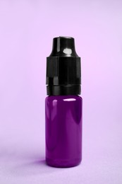 Bottle with purple food coloring on bright background