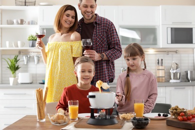 Happy family enjoying fondue dinner at home