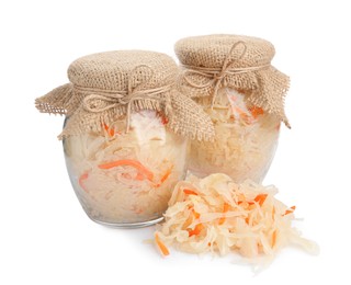 Photo of Glass jars of tasty fermented cabbage with carrot on white background