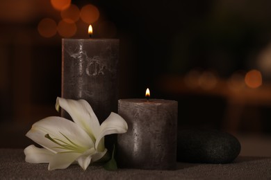 Spa composition with burning candles, lily flower and stone on massage table in wellness center