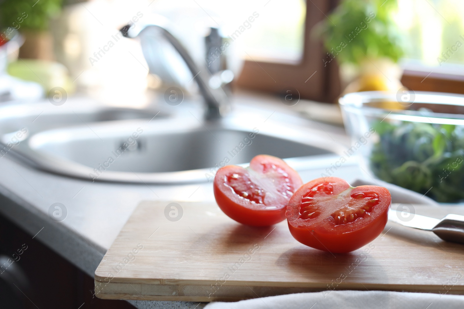 Photo of Halves of fresh raw tomato and knife on countertop in kitchen, closeup. Space for text