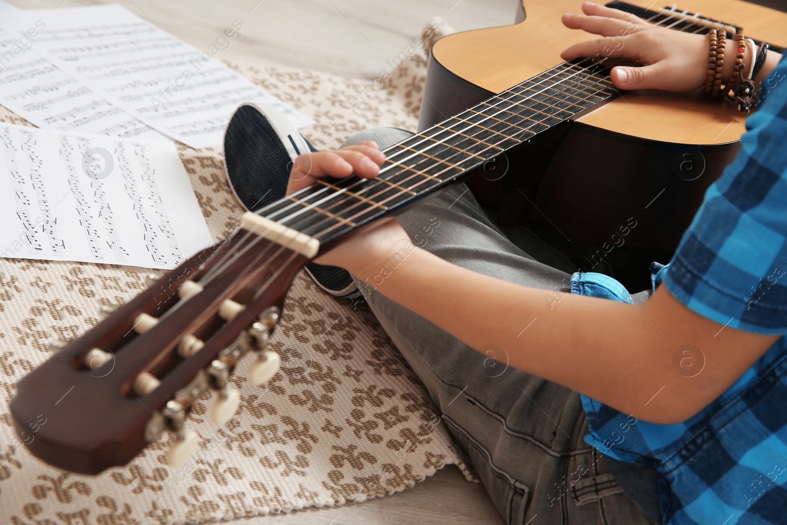 Photo of Little boy playing guitar on floor, closeup