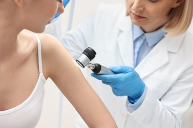 Photo of Dermatologist with dermatoscope examining patient in clinic, closeup