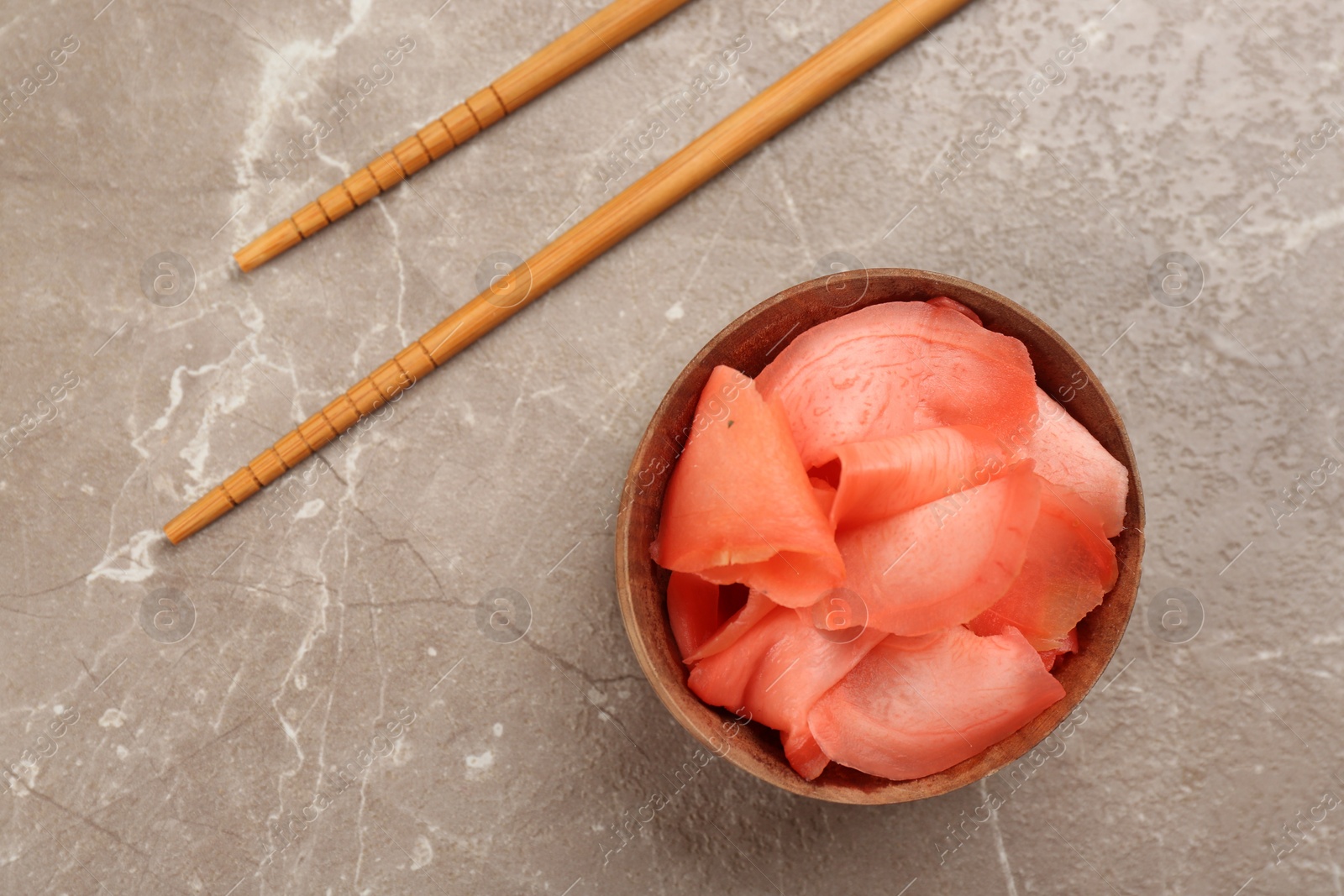 Photo of Spicy pickled ginger and chopsticks on grey table, flat lay