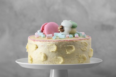 Photo of Delicious cake decorated with macarons and marshmallows against grey background, closeup