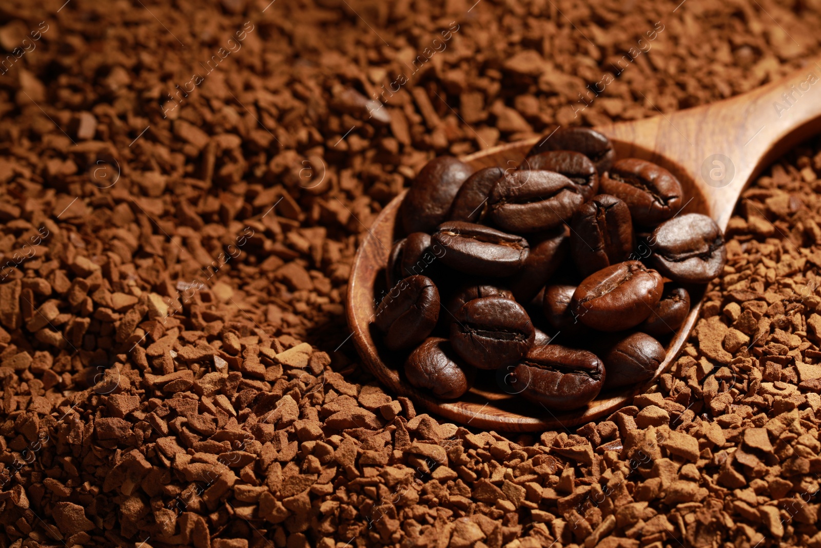 Photo of Spoon with roasted beans on instant coffee, closeup. Space for text