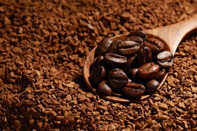 Spoon with roasted beans on instant coffee, closeup. Space for text