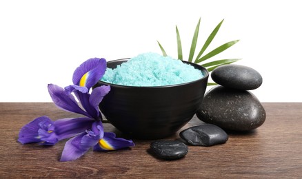 Light blue sea salt in bowl, spa stones, flower and palm leaf on wooden table against white background