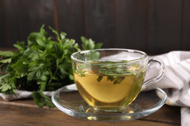 Photo of Aromatic herbal tea with parsley on wooden table, closeup