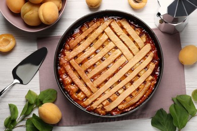 Photo of Delicious apricot pie in baking dish and fresh fruits on white wooden table, flat lay