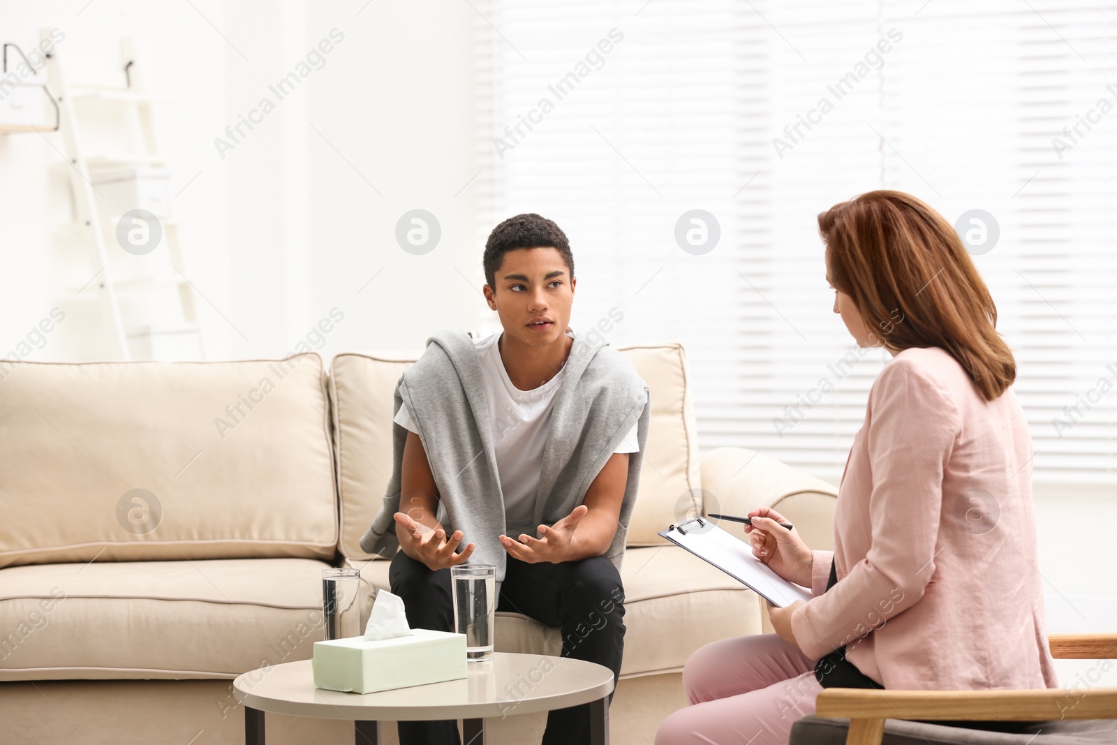 Photo of Psychotherapist working with teenage African-American boy in office