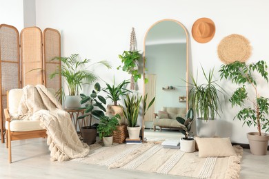 Stylish room interior with wooden furniture and different houseplants near white wall