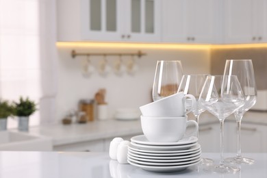 Photo of Set of clean dishware and glasses on table in kitchen, space for text