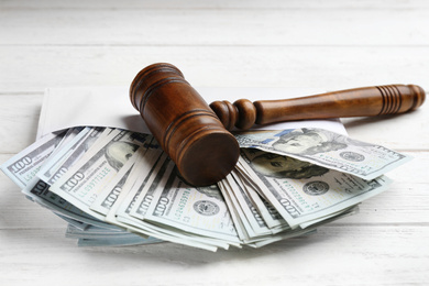 Dollar bills and gavel on white wooden table, closeup. Bribe concept