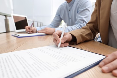 Photo of Woman signing contract at table in office, closeup.