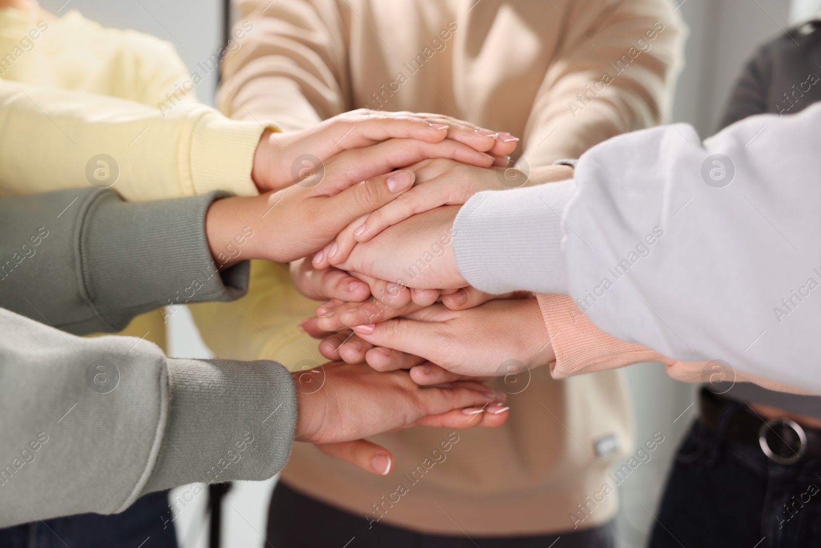 Photo of Group of people holding hands together indoors, closeup. Unity concept