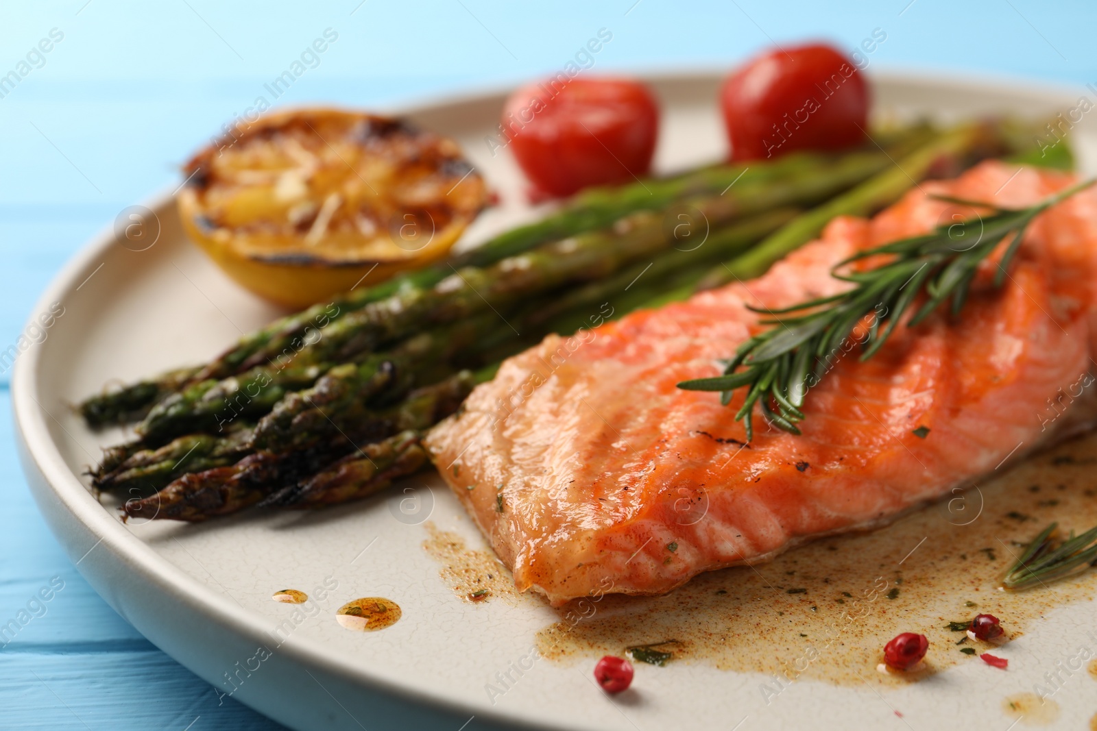 Photo of Tasty grilled salmon with asparagus and spices on plate, closeup