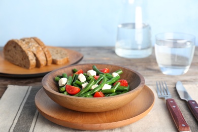 Plate with tasty green beans, tomatoes and cheese on table