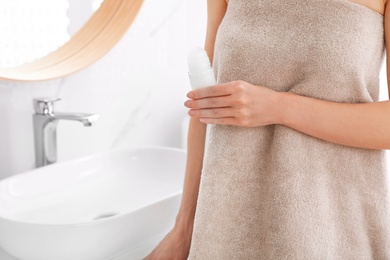 Young woman with roll on deodorant in bathroom, closeup view. Space for text