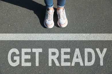 Text Get Ready and line on asphalt in front of woman, closeup view