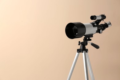 Photo of Tripod with modern telescope on beige background, closeup. Space for text