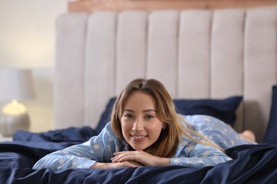 Photo of Young woman lying on comfortable bed with silky linens