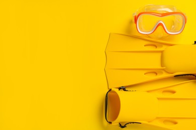 Photo of Pair of flippers and mask on yellow background, flat lay. Space for text