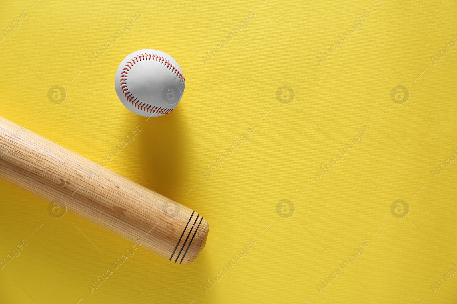 Photo of Baseball bat and ball on yellow background, flat lay. Space for text