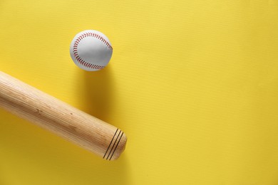 Baseball bat and ball on yellow background, flat lay. Space for text