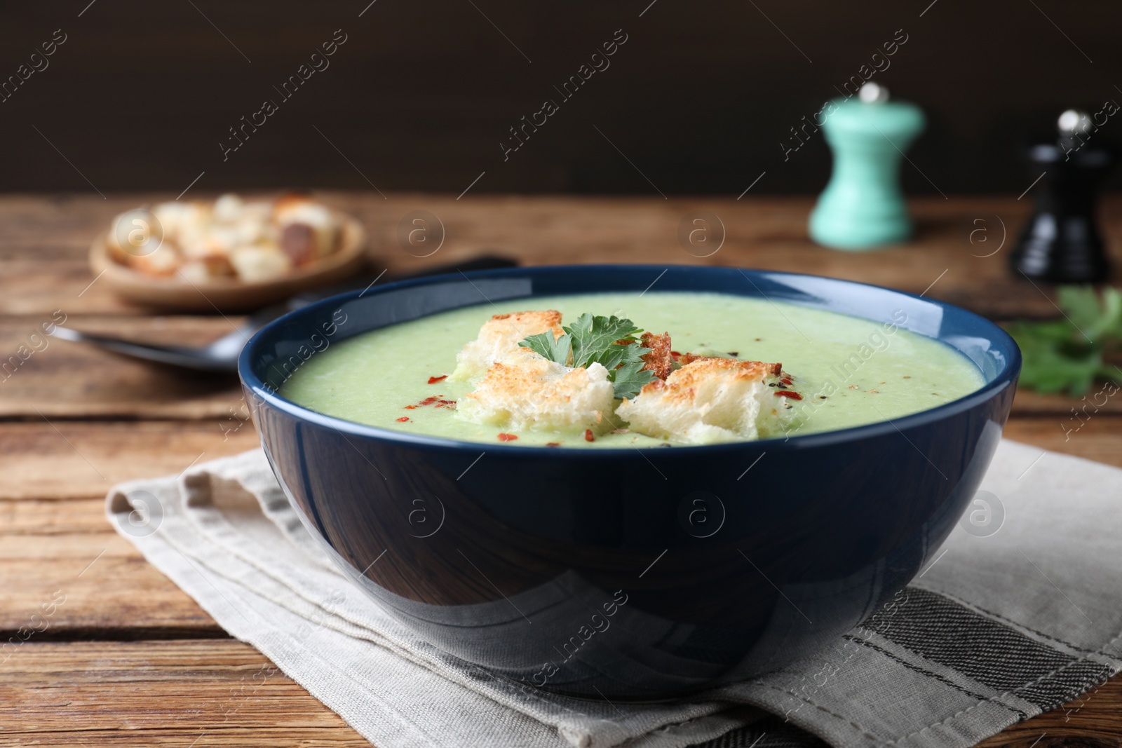 Photo of Delicious asparagus soup with croutons served on wooden table