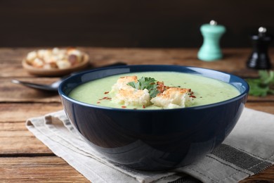 Delicious asparagus soup with croutons served on wooden table