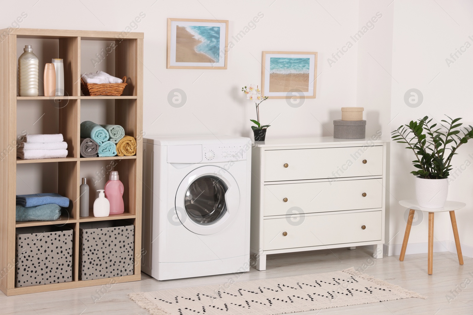 Photo of Stylish laundry room with washing machine and chest of drawers. Interior design