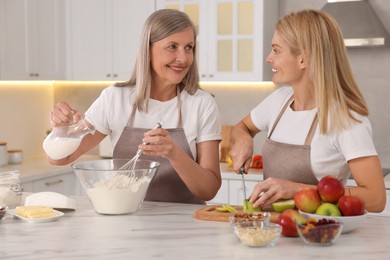 Photo of Happy mature mother and her daughter cooking together at kitchen